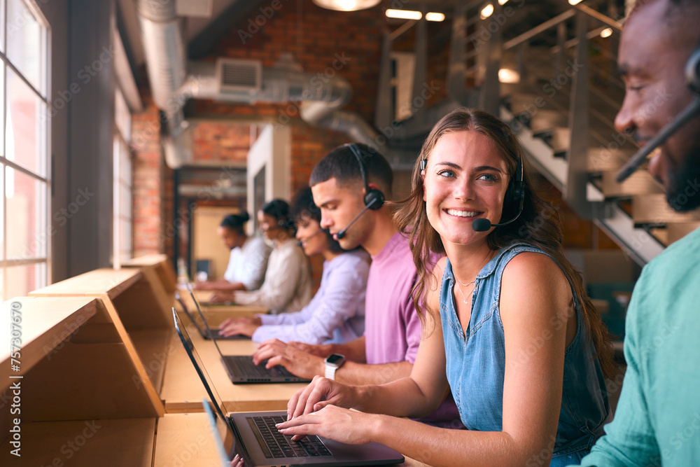 Multi-Cultural Customer Support Or Telesales Team In Modern Open Plan Office Wearing Headsets