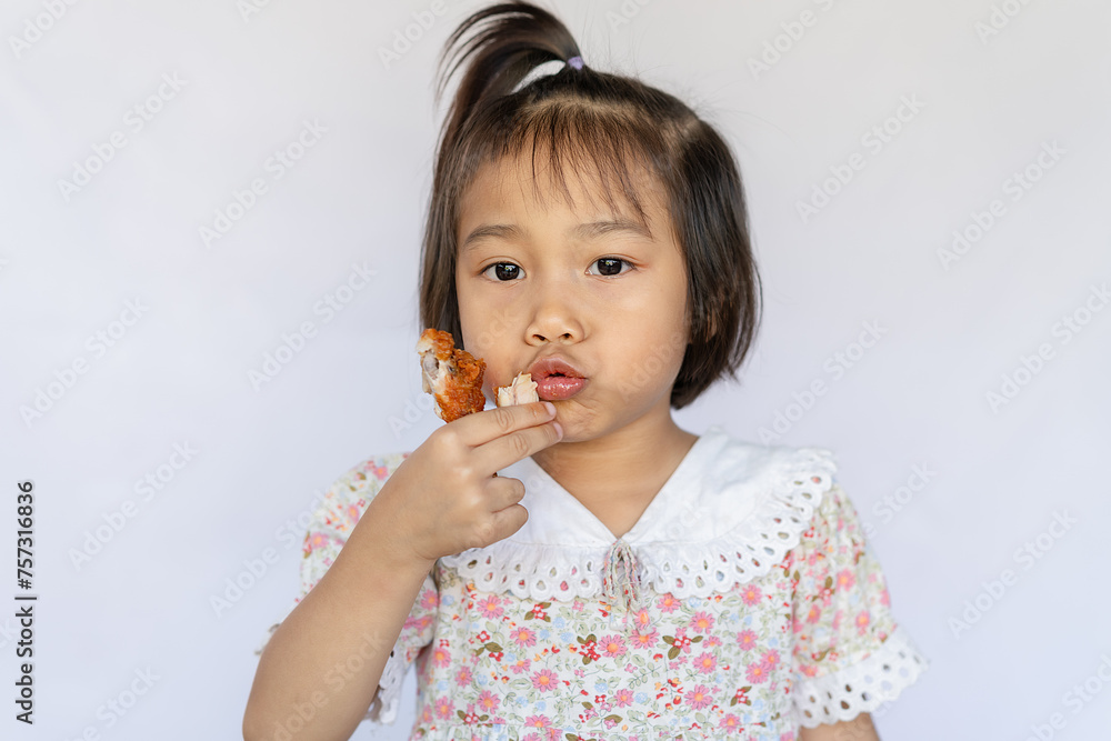 A happy little girl stands interestingly eating crispy fried chicken thighs. , The bright and cute little girl and the delicious fried chicken legs were happy to eat the delicious food. A happy little girl stands interestingly eating crispy fried chicken thighs. , The bright and cute little girl and the delicious fried chicken legs were happy to eat the delicious food.