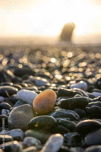 Photography A small rock is sitting on a beach with a large rock in the background