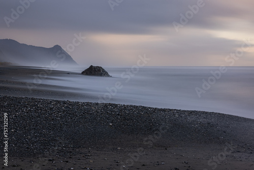 A rocky beach with a large rock in the foreground