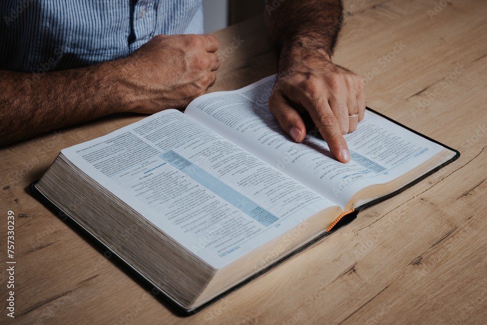 Naklejka premium Man is reading the bible pointing with his finger at the text