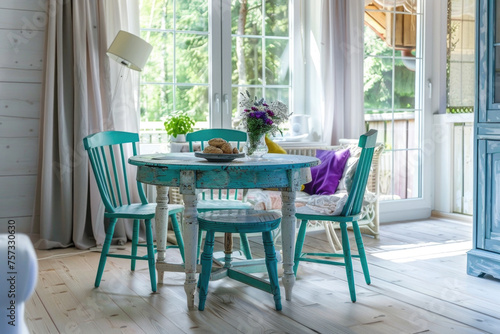 Rustic, vintage furniture, table and chairs of various bright colors in the dining room with large windows.