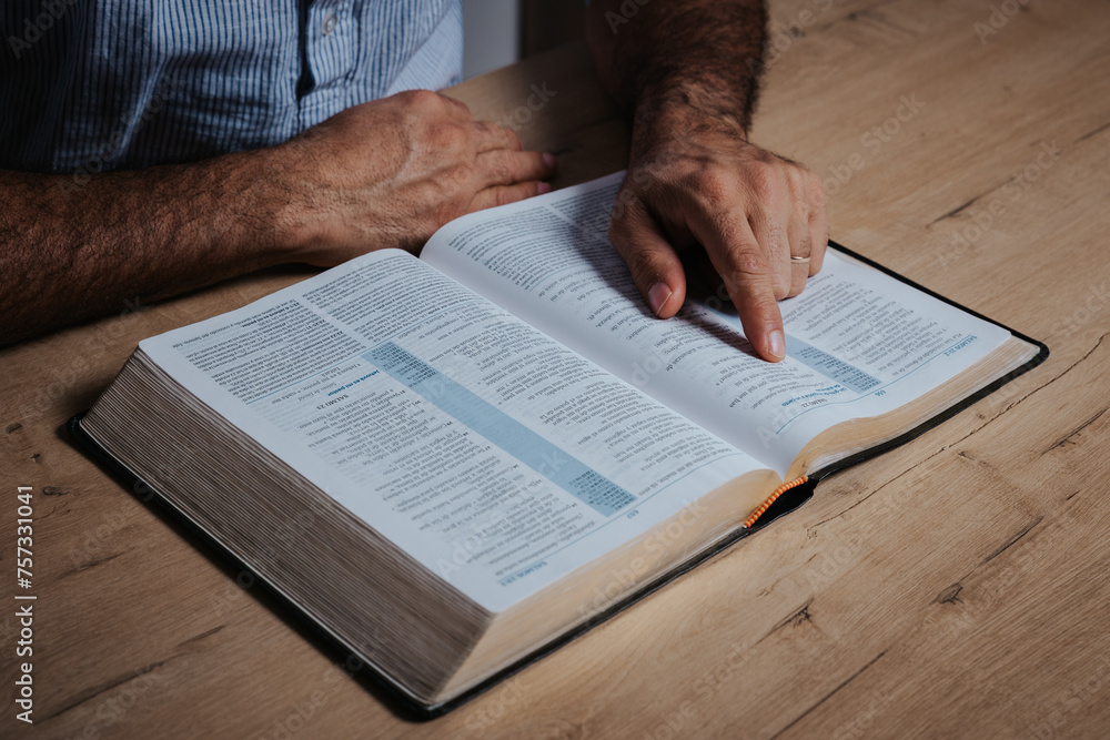 Naklejka premium Man is reading the bible pointing with his finger at the text