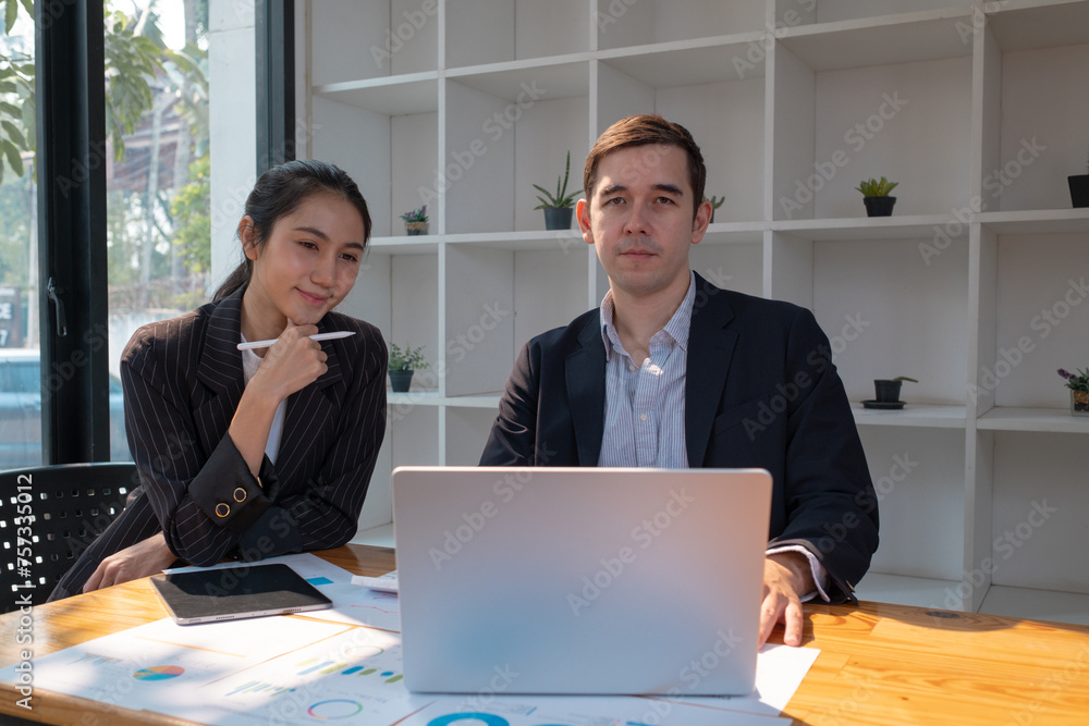 Two business people using a laptop ipad togerher in an office, a man and a women analyzing documents stat at office Two business people using a laptop ipad togerher in an office, a man and a women analyzing documents stat at office