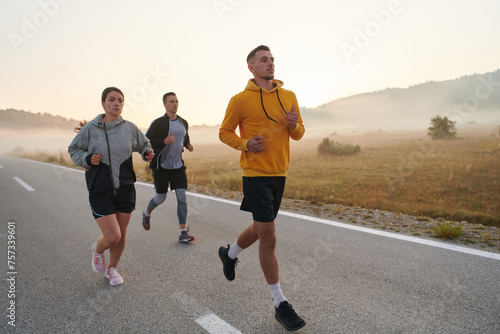 A group of friends, athletes, and joggers embrace the early morning hours as they run through the misty dawn, energized by the rising sun and surrounded by the tranquil beauty of nature