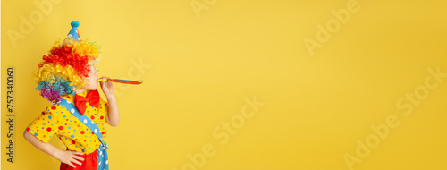 Banner. Funny kid clown against yellow background. Happy child playing with festive decor. Birthday and 1 April Fool s day concept