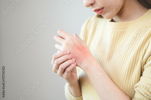 young woman scratching on her arm and has a red rash irritation on her skin from dust intolerance. © Pormezz