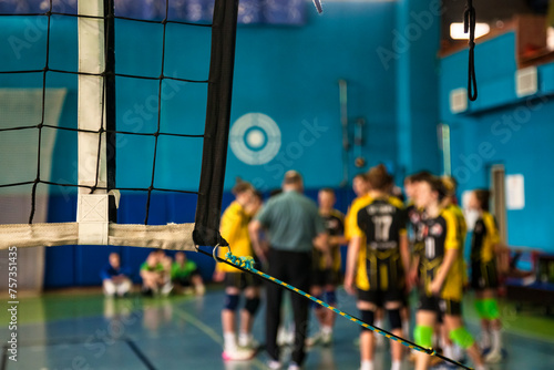 Selective focus of coach analyze play game of volleyball team, timeout active match in sports school gym. Team volleyball game with net. Concept of team sport games, team success. Copy ad text space