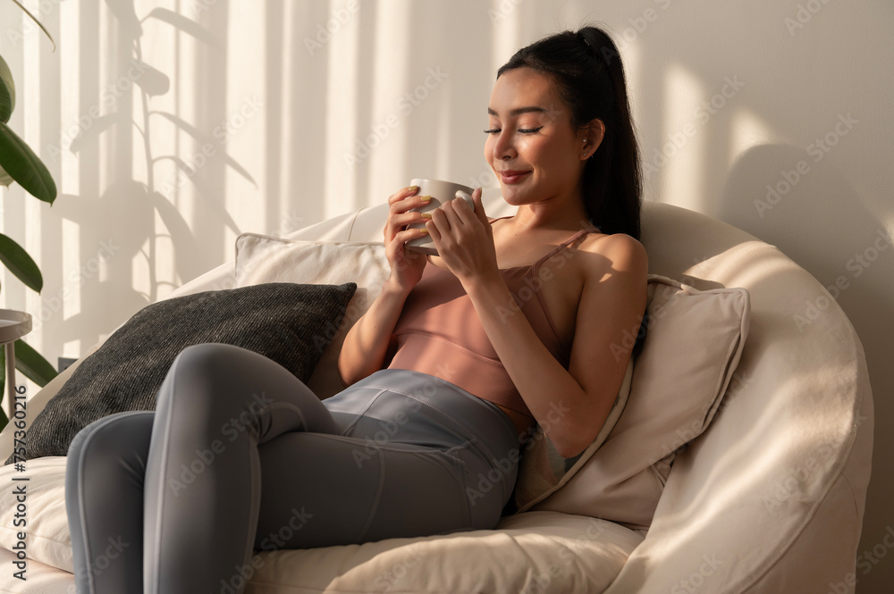Obraz premium Young asian woman enjoying having coffee in living room at home