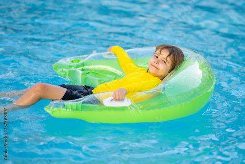 Child play in pool on inflatable ring. Kid with inflatable ring in swimming pool. Child water toys. Children play in tropical resort. Child in swiming pool. Kid floating in sea.
