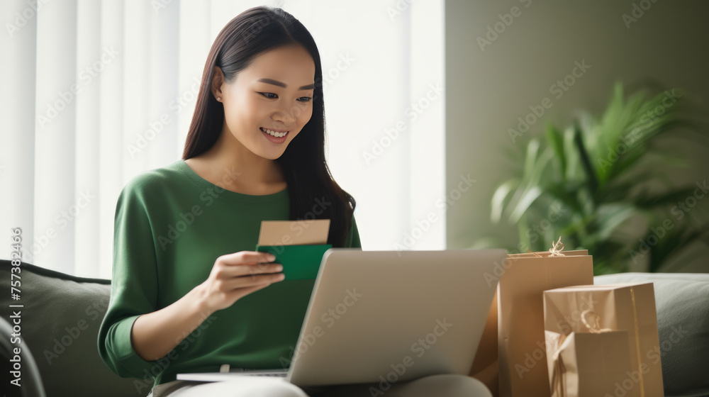 Woman at home, holding a credit card and looking at a laptop screen making order Woman at home, holding a credit card and looking at a laptop screen making order