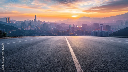 Asphalt highway road and mountains with city skyline at sunset