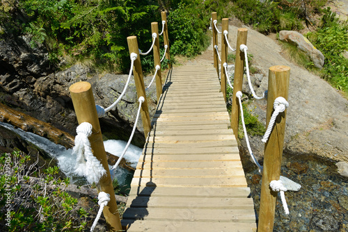 Pedestrian wooden bridge over mountain river. © Serghei V