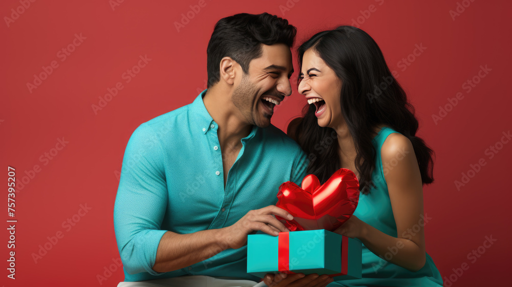 Cheerful man and woman closely facing each other, smiling joyfully while holding a red gift between them. Cheerful man and woman closely facing each other, smiling joyfully while holding a red gift between them.