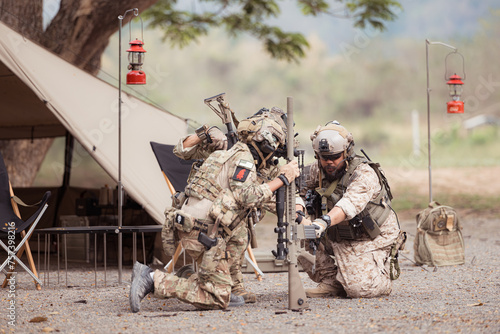 Group of soldiers in camouflage uniforms hold weapons in front of camp tent  Plan and prepare for combat training.