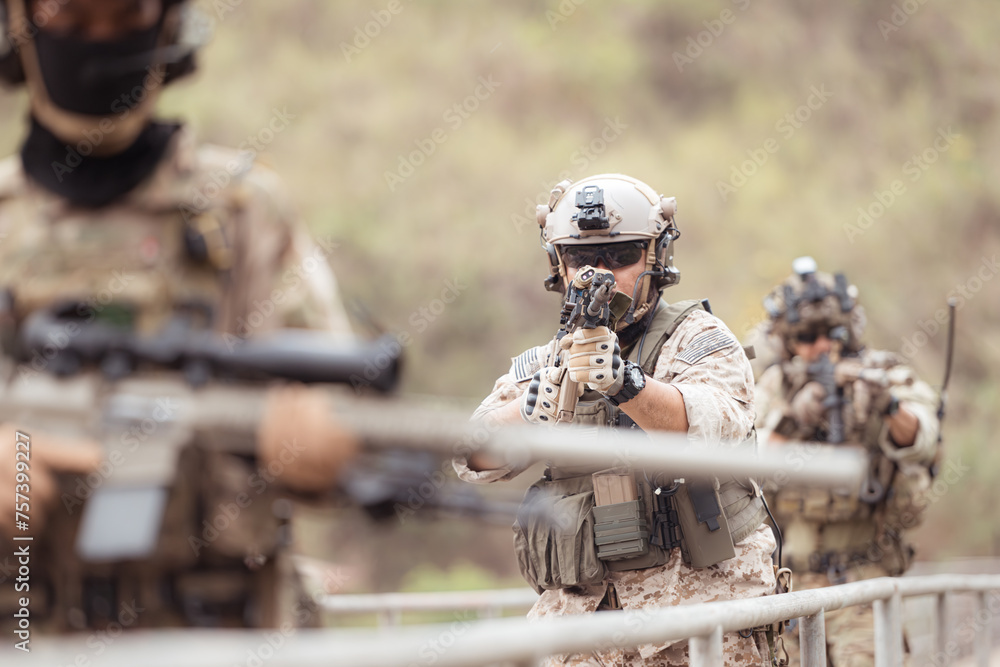 Fototapeta premium Soldiers in camouflage military uniforms carrying weapons, Reconnaissance missions in the tropical forest area, Assault infantry battle training.
