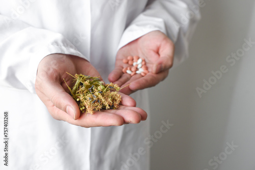 Choosing between natural medicine and synthetic, doctor's hands holding herbs and pills