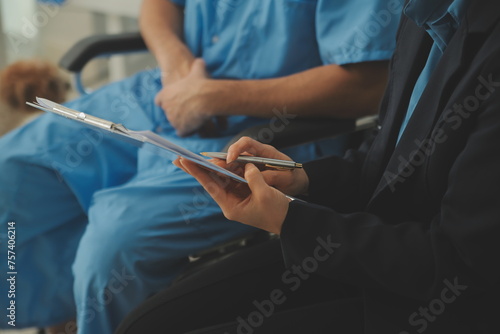 Midsection of female nurse checking blood pressure of woman sitting on wheelchair in clinic