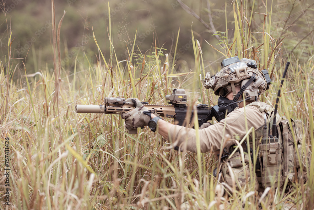 Fototapeta premium Soldiers in camouflage military uniforms carrying weapons, Reconnaissance missions in the tropical forest area, Assault infantry battle training.