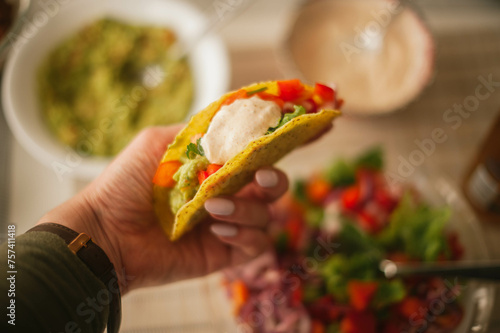 A hand delicately holds a freshly made taco, brimming with flavorful Mexican fillings, promising a savory culinary experience