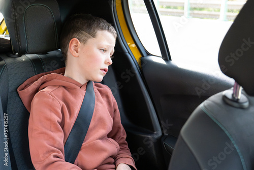 Young boy wearing seatbelt in car looking away