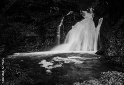 A black and white portrayal of the Rio Mundo Waterfall's vigorous cascade, creating a striking contrast with the surrounding rocks photo