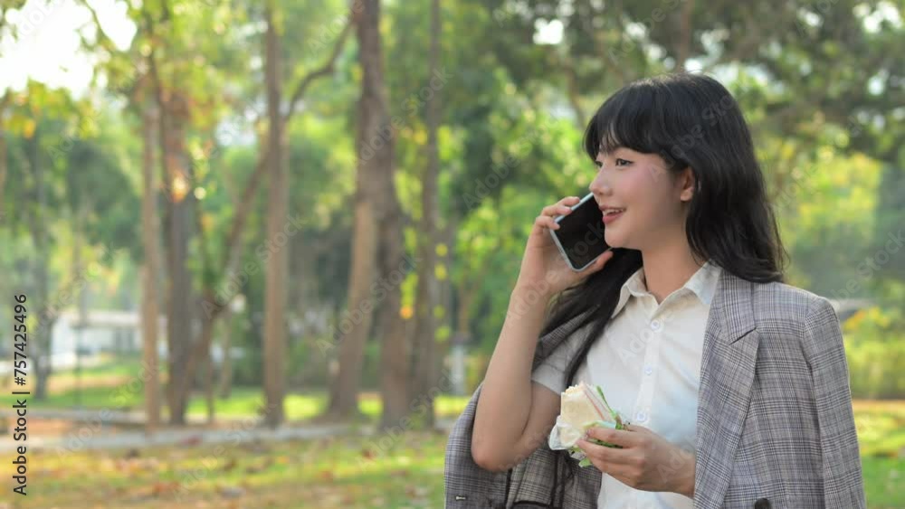 Happy young businesswoman holding sandwich and talking on mobile phone at outdoor Happy young businesswoman holding sandwich and talking on mobile phone at outdoor