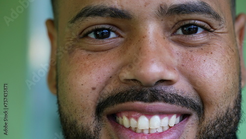 Macro close-up portrait of a hispanic black latin man smiling at camera. Tight closeup of South American person in 20s wide grin