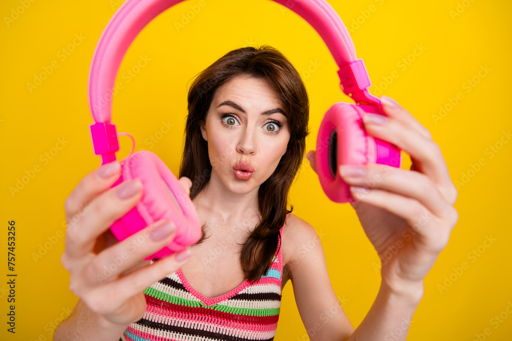 Portrait of funny woman wear knit tank recommend you check out impressive earphones sound isolated on vivid yellow color background Portrait of funny woman wear knit tank recommend you check out impressive earphones sound isolated on vivid yellow color background