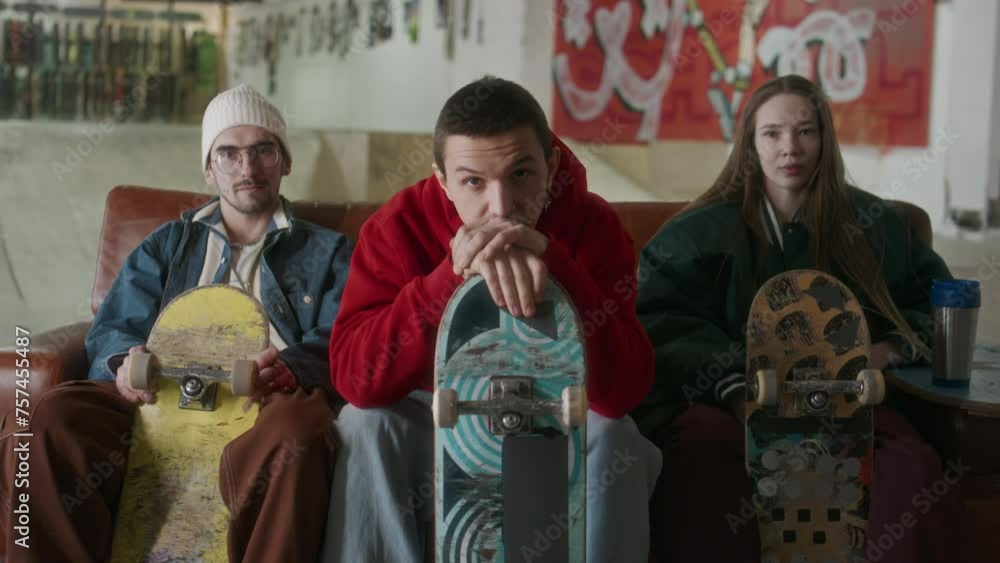 Group portrait of young friends in streetwear sitting on couch with skateboards and posing together for camera Group portrait of young friends in streetwear sitting on couch with skateboards and posing together for camera