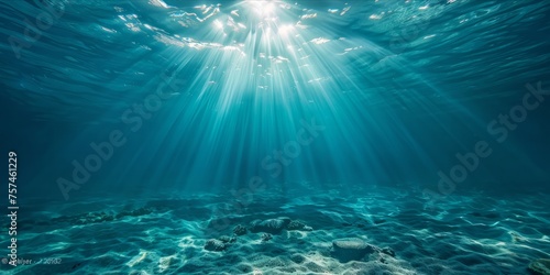 Underwater view with sun rays shining through the ocean surface. © ParinApril