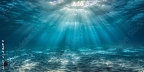 Underwater view with sun rays shining through the ocean surface. © ParinApril