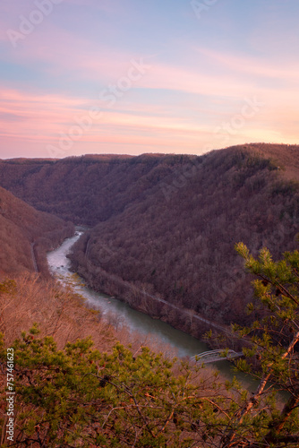 Vertical view of winding river in canyon flowing through dense tree covered mountains at New River Gorge National Park during sunset
