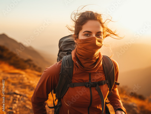 An adventurous hiker with a backpack treks through the mountains during a warm, golden sunset.