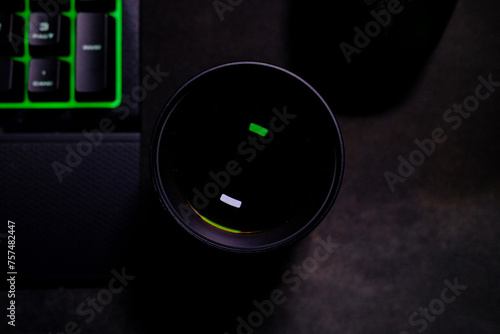 Obiettivo fotocamera visto dall'alto con riflesso appoggiato su scrivania con tastiera e mouse da gaming