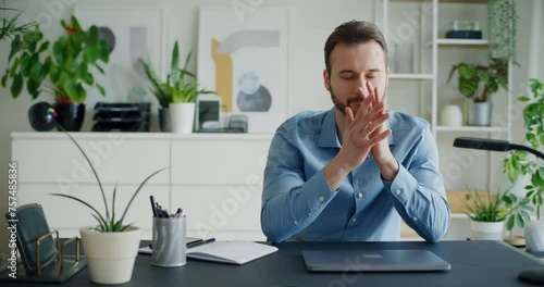 Worried businessman closing laptop sitting with hands clasped photo