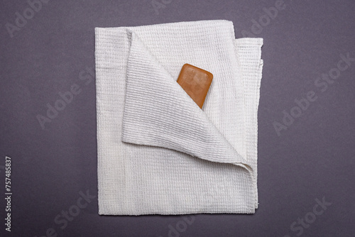 Simple laundry soap and white waffle towel on a gray background. Minimalism and cleanliness.