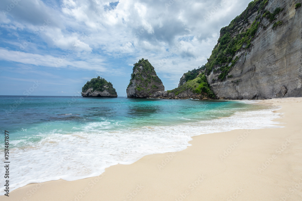 Scenery of sunny day with sand beach, turquoise ocean, blue sky, waves and mountains. View of Diamond beach, Nusa Penida, Bali island, Indonesia. Wallpaper background. Natural scenery. Scenery of sunny day with sand beach, turquoise ocean, blue sky, waves and mountains. View of Diamond beach, Nusa Penida, Bali island, Indonesia. Wallpaper background. Natural scenery.