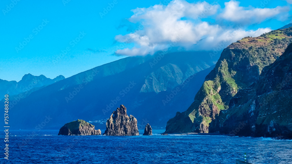 Panoramic view of volcanic rock formation Ilheus da Janela in coastal town Porto Moniz, Madeira island, Portugal, Europe. Rugged cliffs of coastline of majestic Atlantic Ocean. Massive mountain ridges Panoramic view of volcanic rock formation Ilheus da Janela in coastal town Porto Moniz, Madeira island, Portugal, Europe. Rugged cliffs of coastline of majestic Atlantic Ocean. Massive mountain ridges