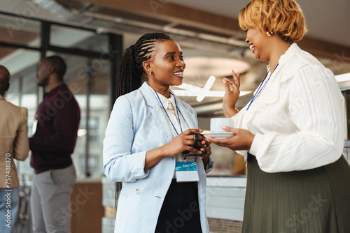 Foto Professional women networking at a business conference, holding coffee and chatt
