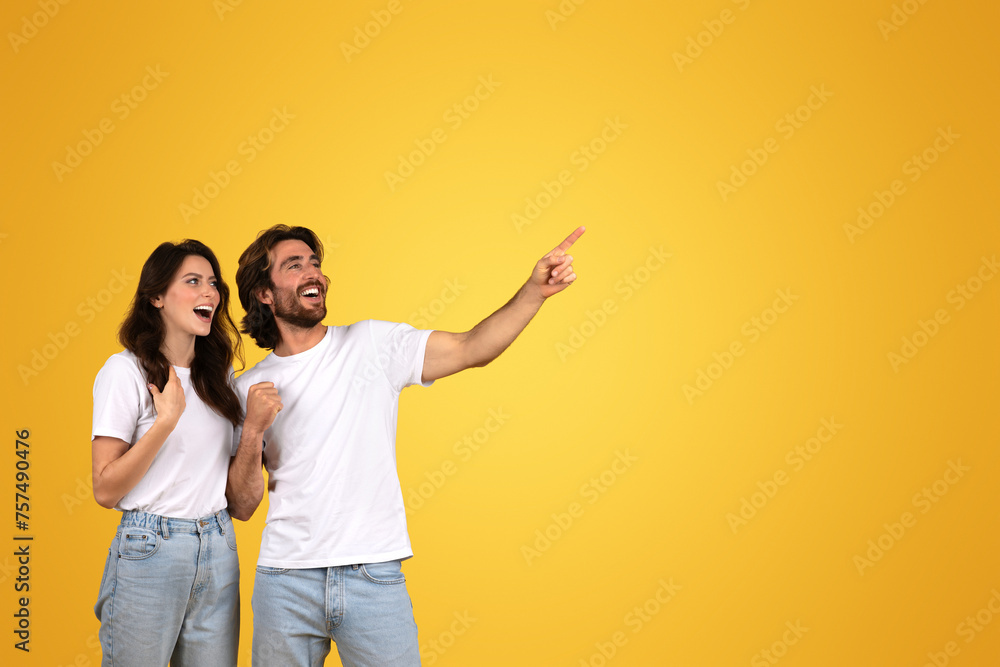 Ecstatic couple with eyes wide open, man pointing and looking to the side with excitement Ecstatic couple with eyes wide open, man pointing and looking to the side with excitement