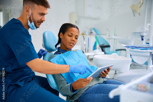 Black woman and her dentist using digital tablet at dentist s office.