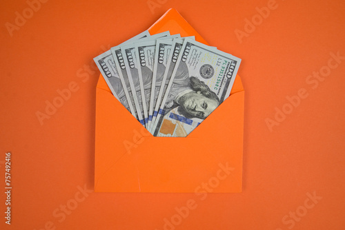Top view of an orange envelope with dollars