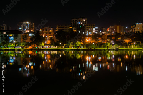 View of living house, apartment, residential buildings facades with illuminated windows with reflection in the water surface in Batumi at night. Architecture, urban, and cityscape concept
