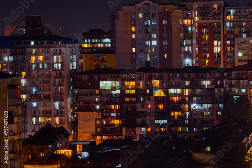 Front view of typical georgian multi storey apartment, residential buildings facade with warm illuminated windows and night lighting, illumination in Batumi, Georgia