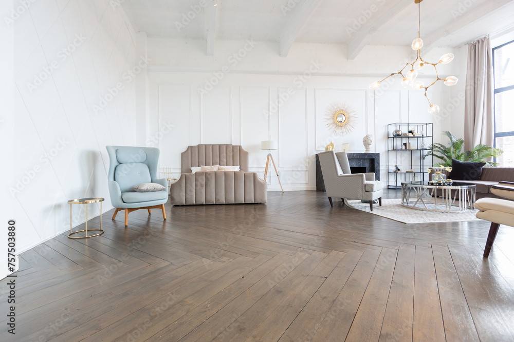 Fototapeta premium Modern luxury stylish apartment interior in pastel colors. a very bright room with huge windows filled with daylight. white walls, wooden parquet floors and a dark marble fireplace