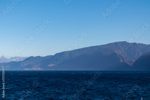 Panoramic view of idyllic rugged cliffs of coastline of majestic Atlantic Ocean seen from coastal town Porto Moniz, Madeira island, Portugal, Europe. Mountain ridges rising majestically from shoreline