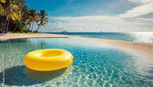 Yellow inflatable ring floating along sandy beach. Tropical sea coast. Summer vacation at the ocean.