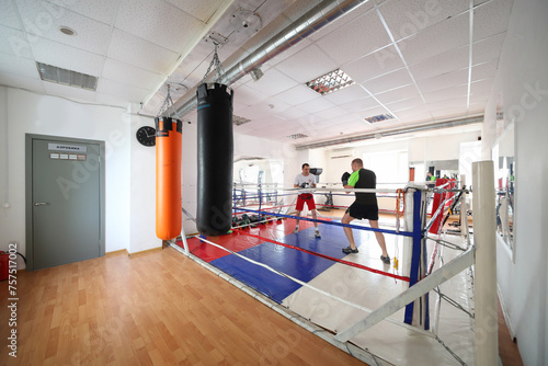 Two man fight in modern gym  with boxing ring, In addition to standard set of fitness services 