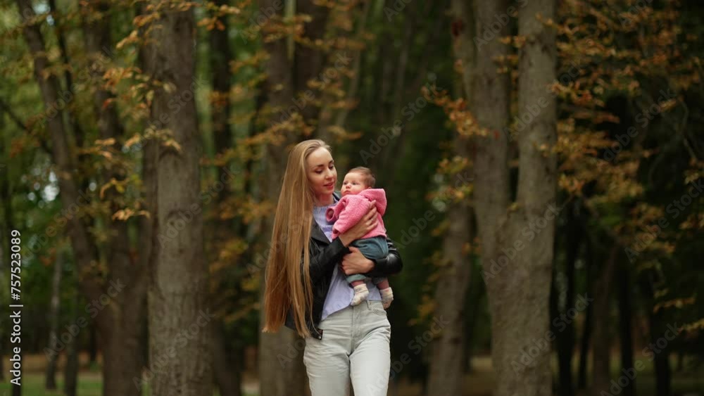 Mother's Contented Walk with Baby in the Autumn Forest. A young mother strolls through an autumnal forest, holding her baby close, surrounded by the changing leaves. Concept Autumn Stroll Mother's Contented Walk with Baby in the Autumn Forest. A young mother strolls through an autumnal forest, holding her baby close, surrounded by the changing leaves. Concept Autumn Stroll